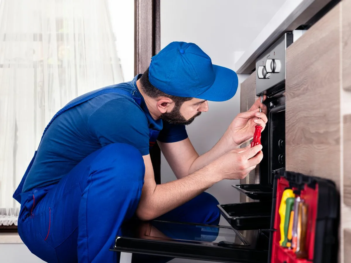 Appliance technician repairing a stove and oven in a Westville, South Africa kitchen.