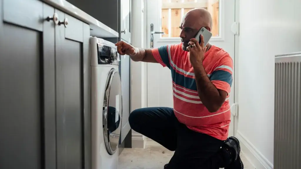 A technician repairing a washing machine in a home in New Germany