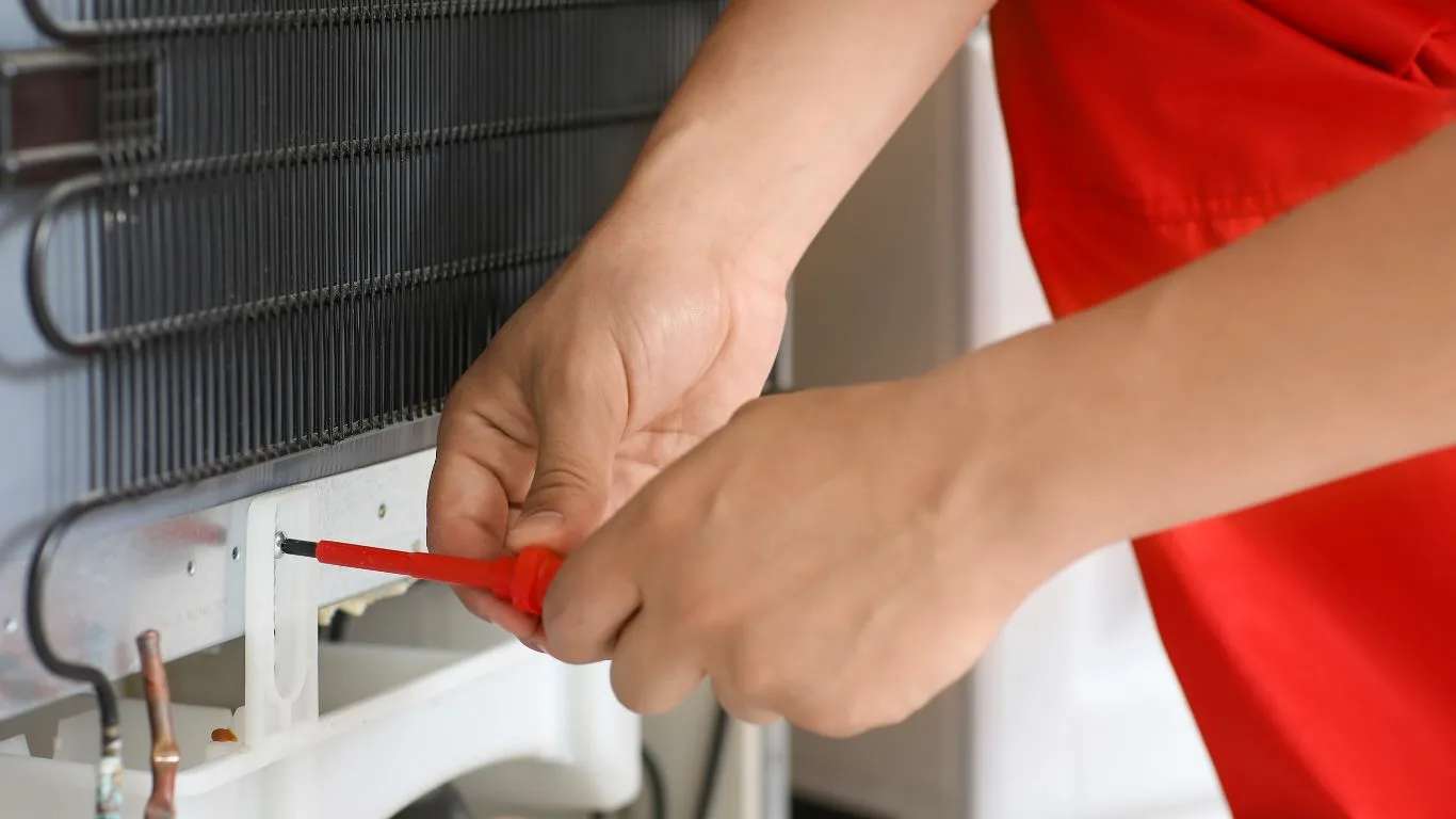 Close-up of hands fixing a Hisense fridge in Durban.