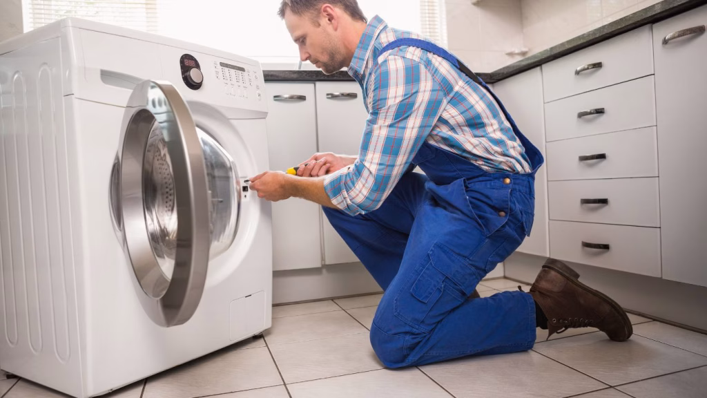 Technician performing washing machine repairs in a Durban home setting