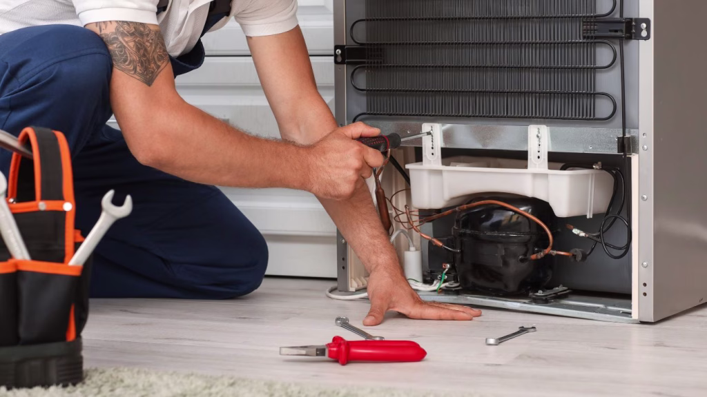 Technician performing local fridge repairs in a Mobeni kitchen setting”