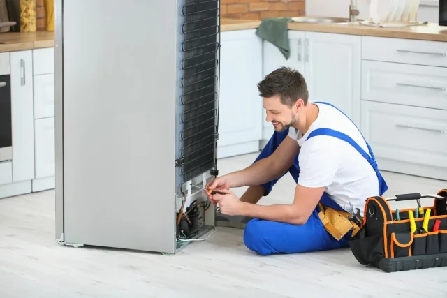 Self-defrosting fridge freeze problems with ice buildup.- a repair man busy on a job